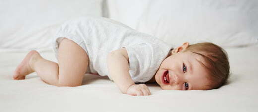 Playful baby having fun in bed